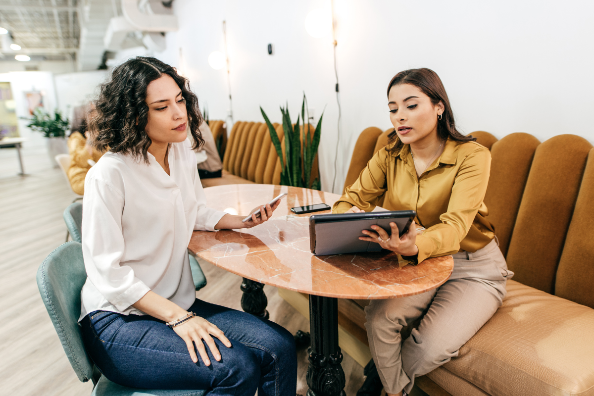 Two professional women meeting at a cafe to talk about business