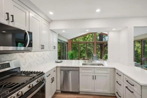 U-shaped light gray shaker kitchen design with peninsula and black hardware