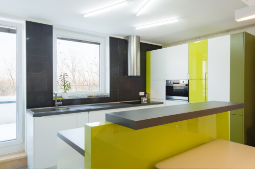 U-shaped white high-gloss kitchen cabinets with lime green accent cabinets, dark gray quartz countertops and a stainless round chimney hood