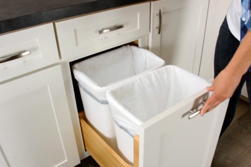 White shaker kitchen cabinets with a pull-out trash cabinet