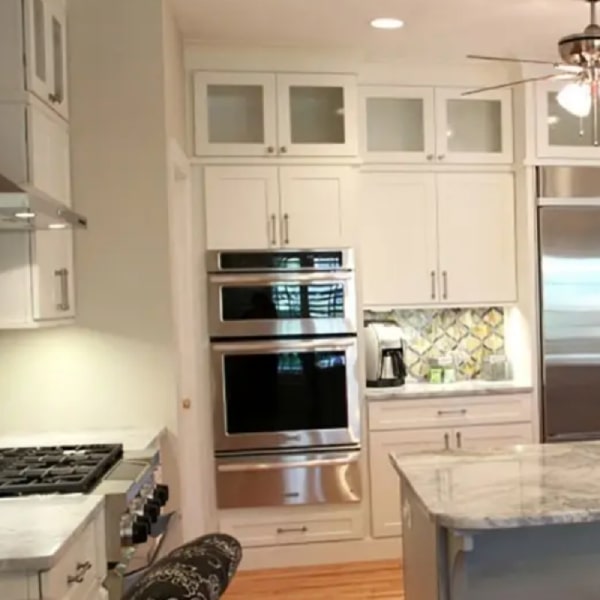 White shaker kitchen with stacked glass cabinets and wall oven with warming drawer