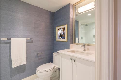 White shaker vanity with white countertops in a blue bathroom