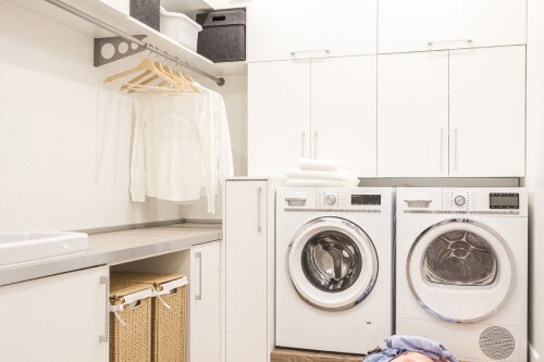 White slab laundry room design with hanging rod above countertops