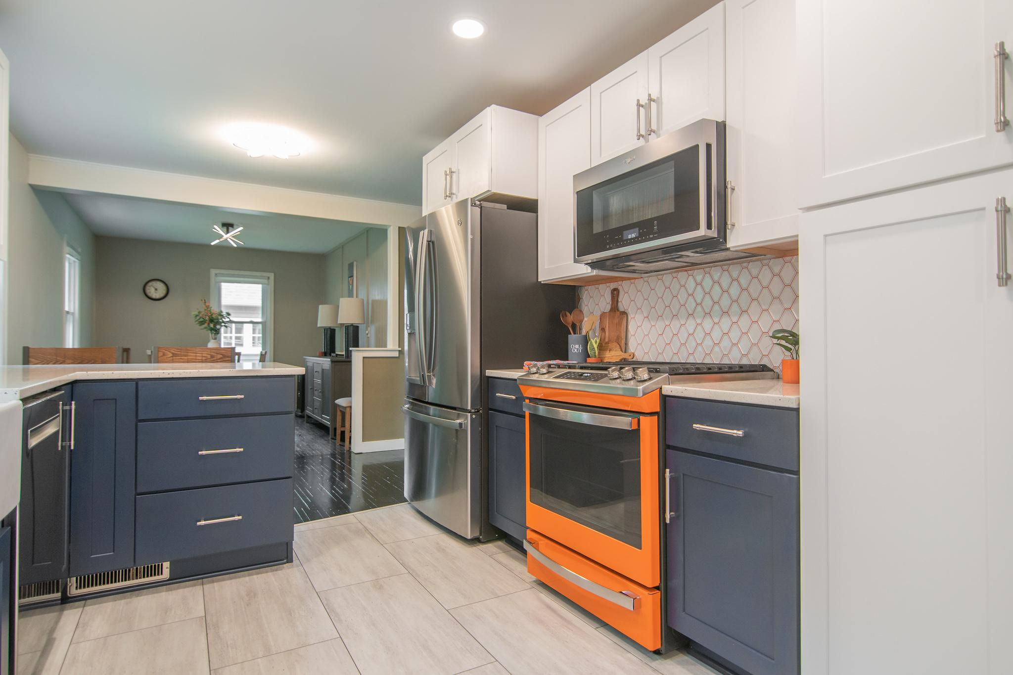 CliqStudios project: White and blue shaker kitchen cabinets with bright orange range and backsplash grout