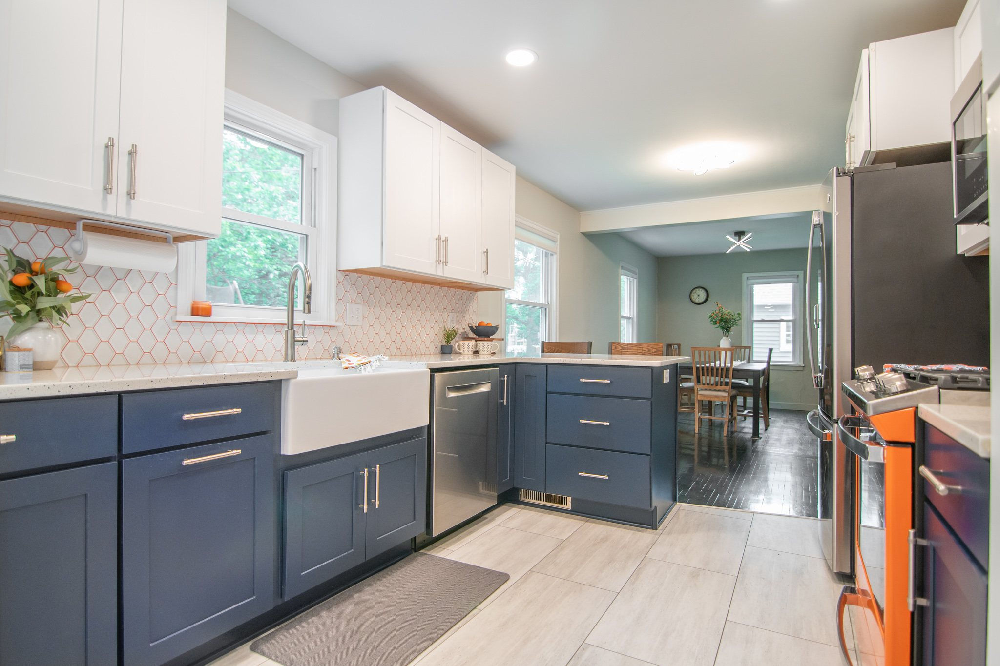 CliqStudios project: White and blue shaker kitchen cabinets with bright orange range and backsplash grout