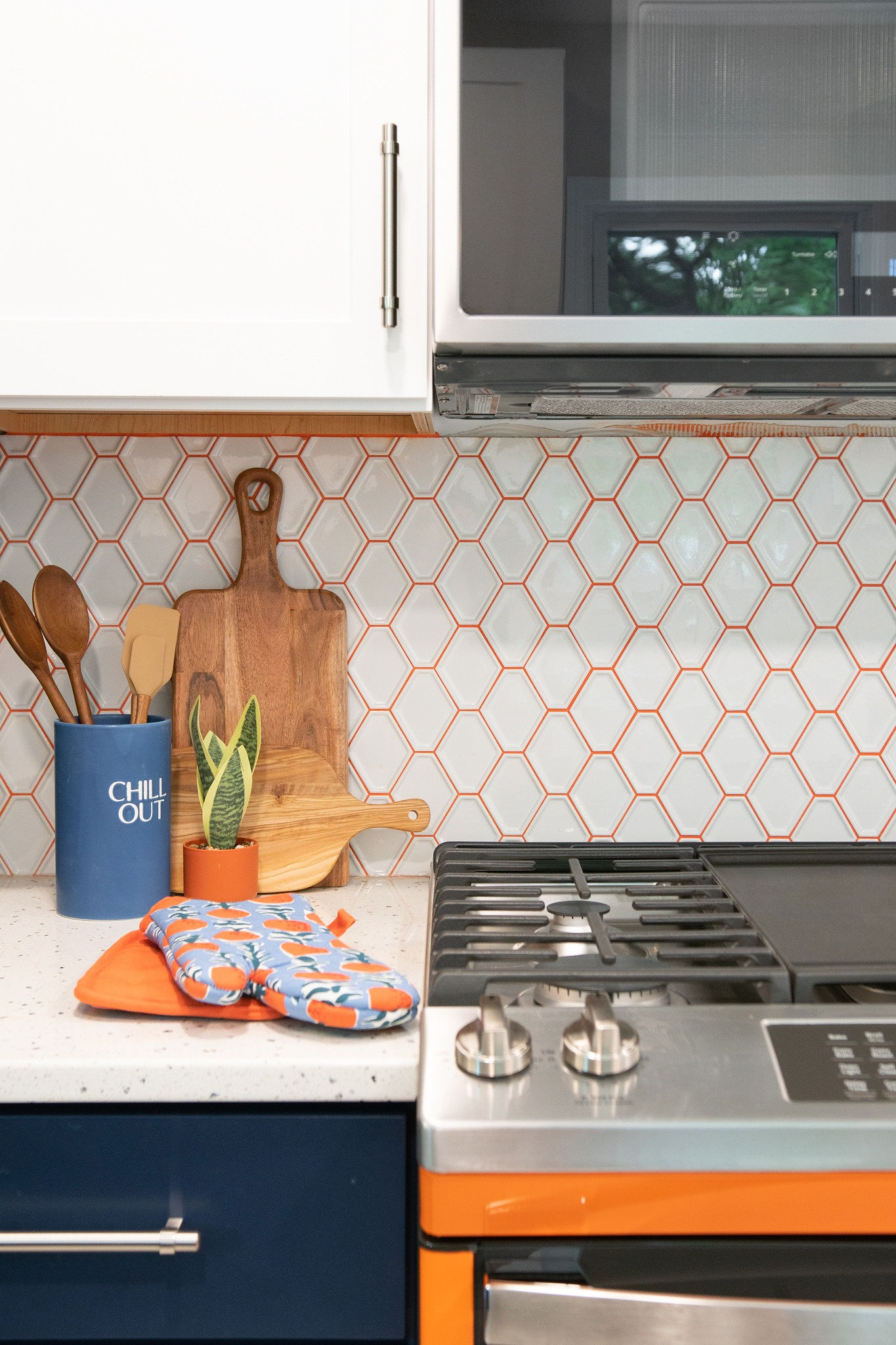 CliqStudios project: White and blue shaker kitchen cabinets and white tile backsplash with orange grout and range