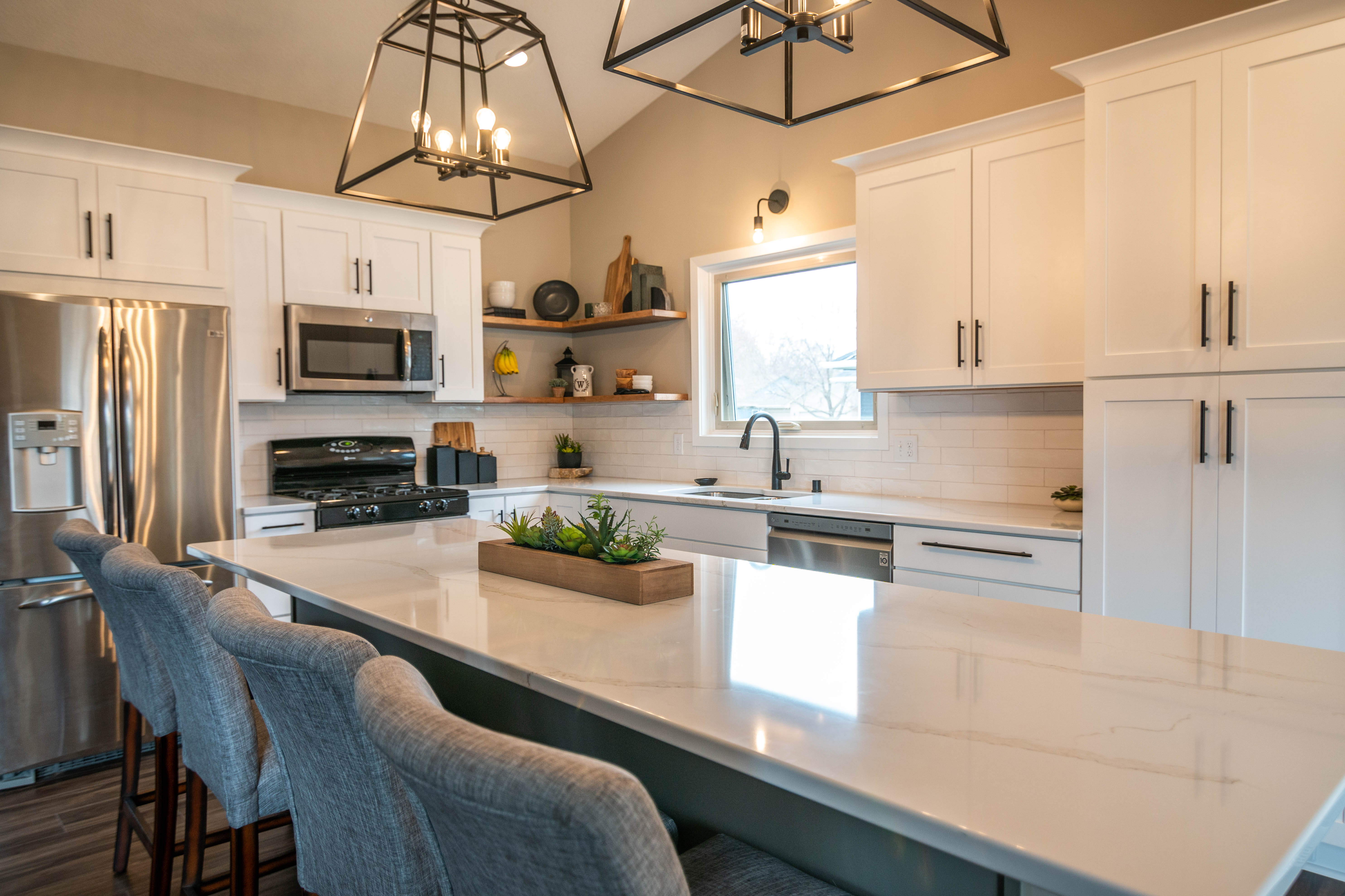 CliqStudios project: White shaker kitchen cabinets with a gray island, white quartz countertops and bronze accents