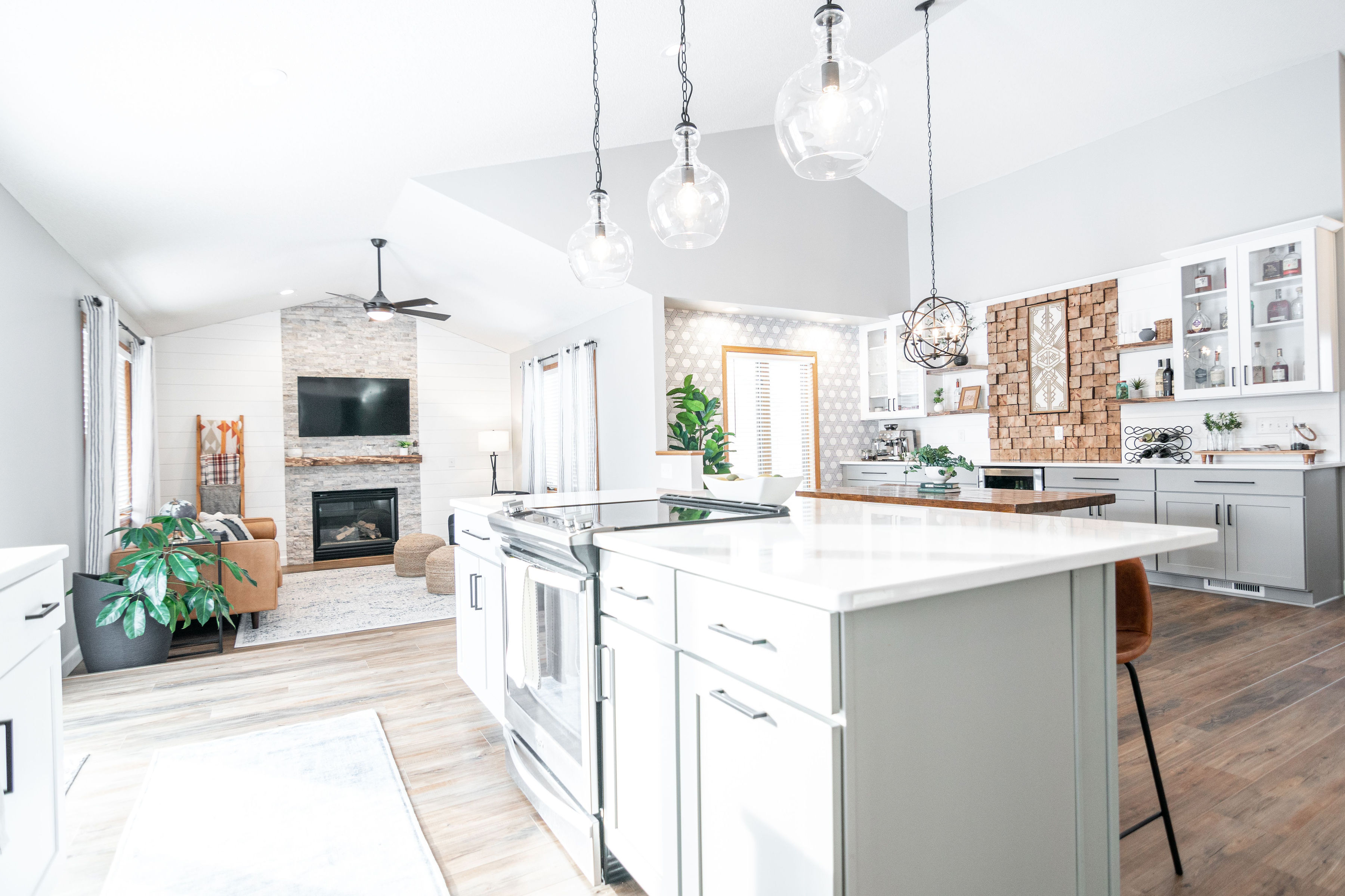 CliqStudios project: White and light gray shaker kitchen cabinets with dark cabinet hardware, light wood accents, and modern decor