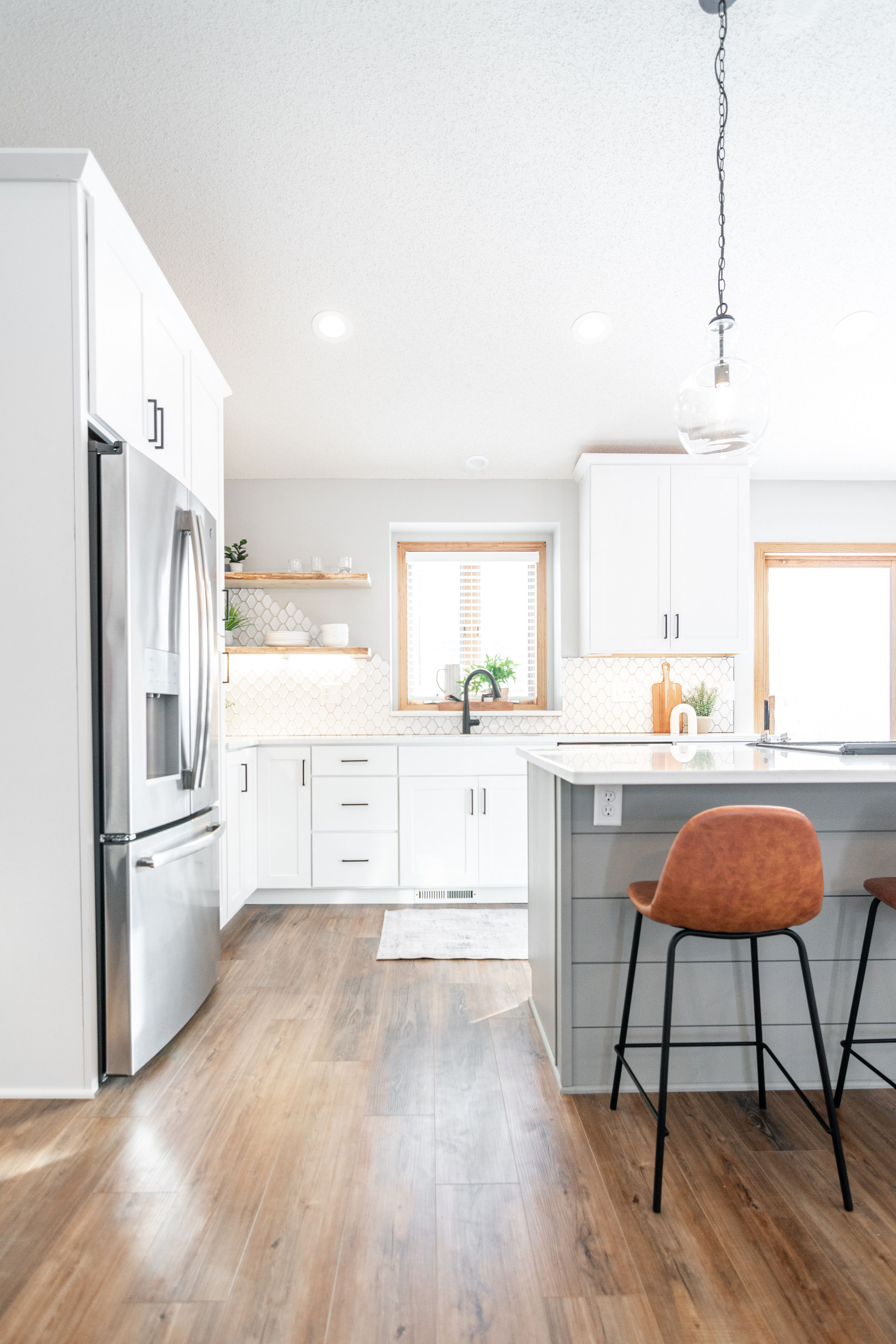 CliqStudios project: White and light gray shaker kitchen cabinets with dark cabinet hardware, light wood accents, and modern decor