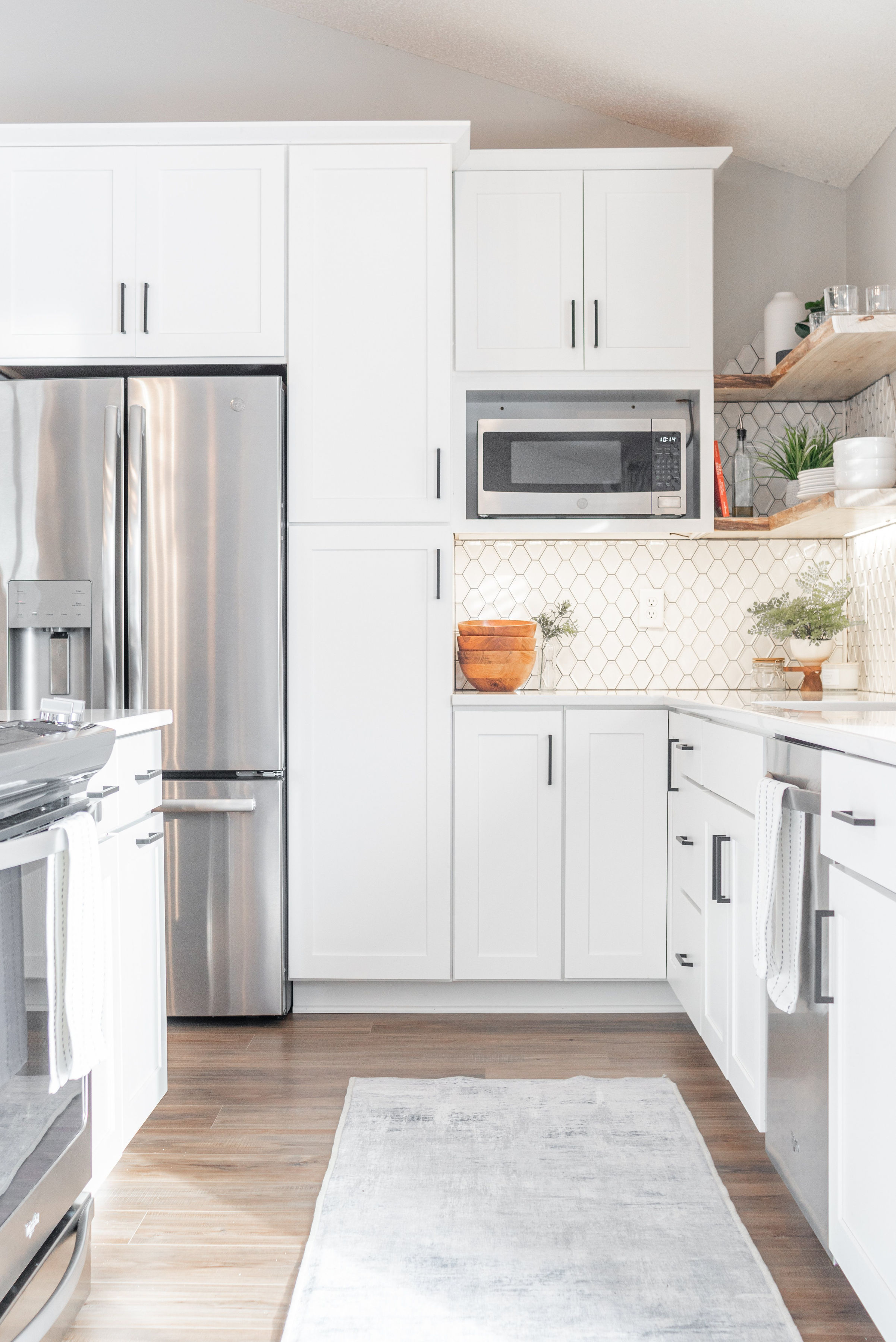 CliqStudios project: White and light gray shaker kitchen cabinets with dark cabinet hardware, light wood accents, and modern decor