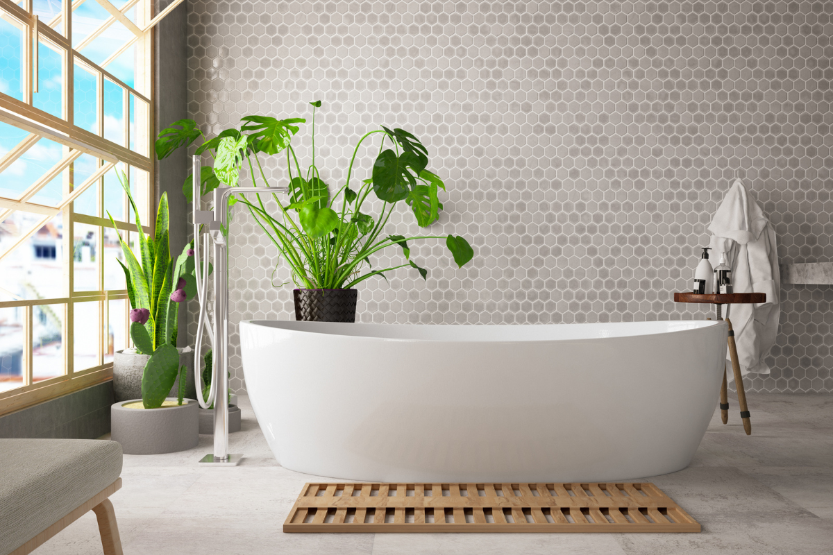 Modern organic bathroom design with white freestanding bathtub in front of focal wall with hexagon brown tiles