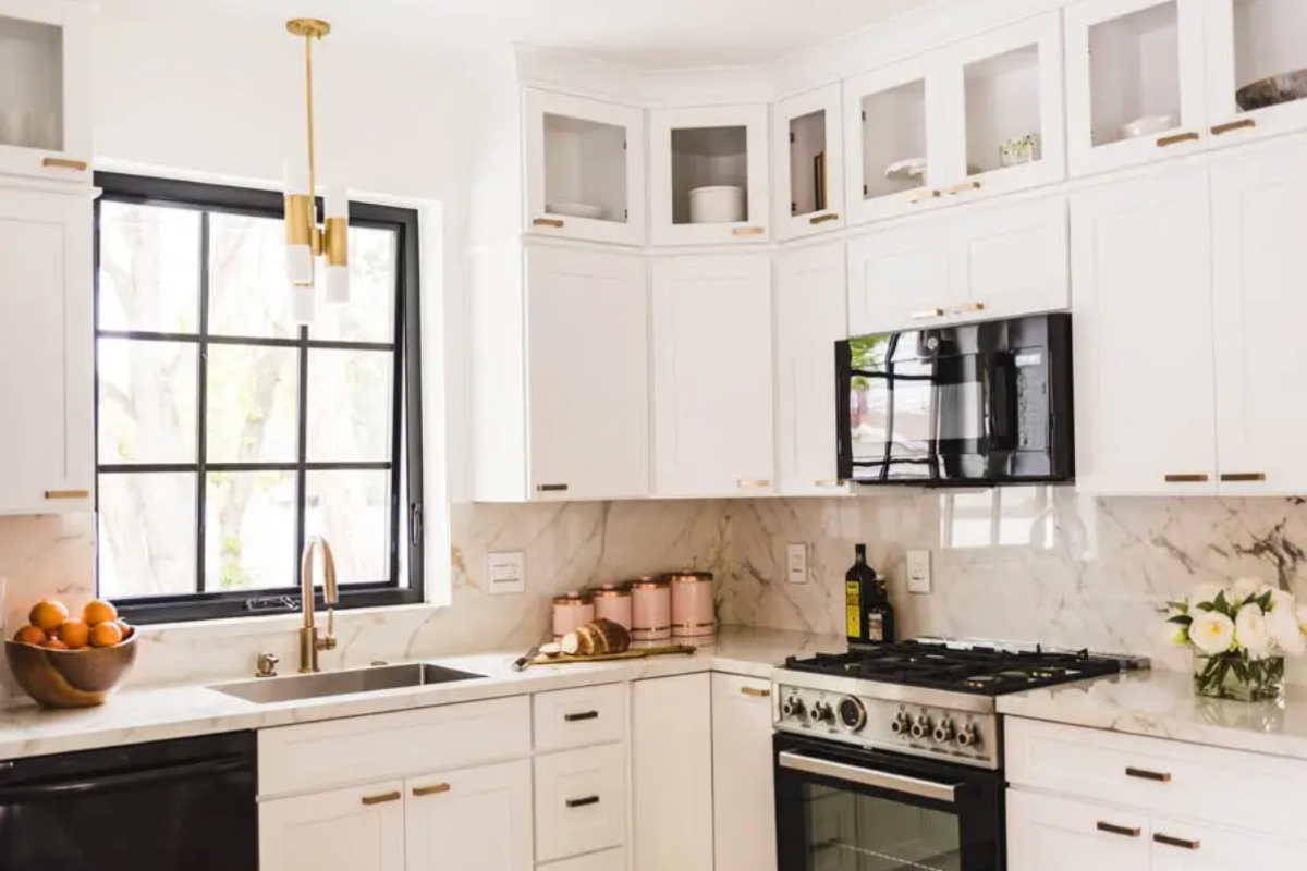 Stacked white shaker kitchen cabinets with glass on top and horizontal brass cabinet hardware