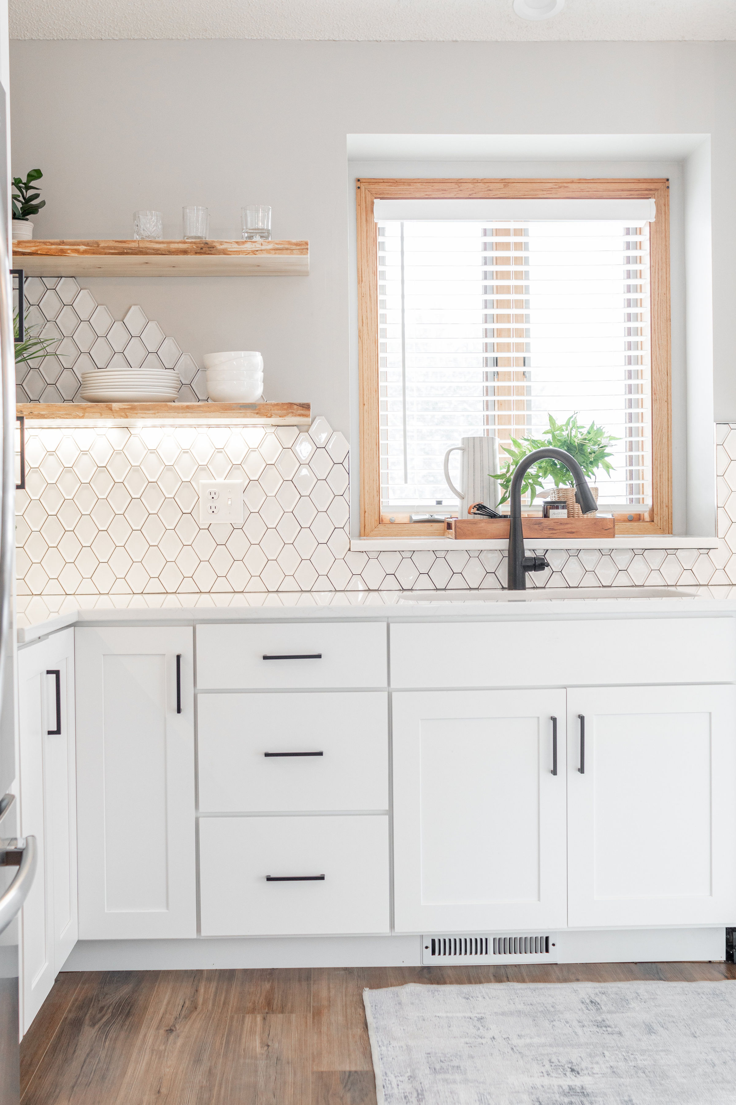 CliqStudios project: White and light gray shaker kitchen cabinets with dark cabinet hardware, light wood accents, and modern decor