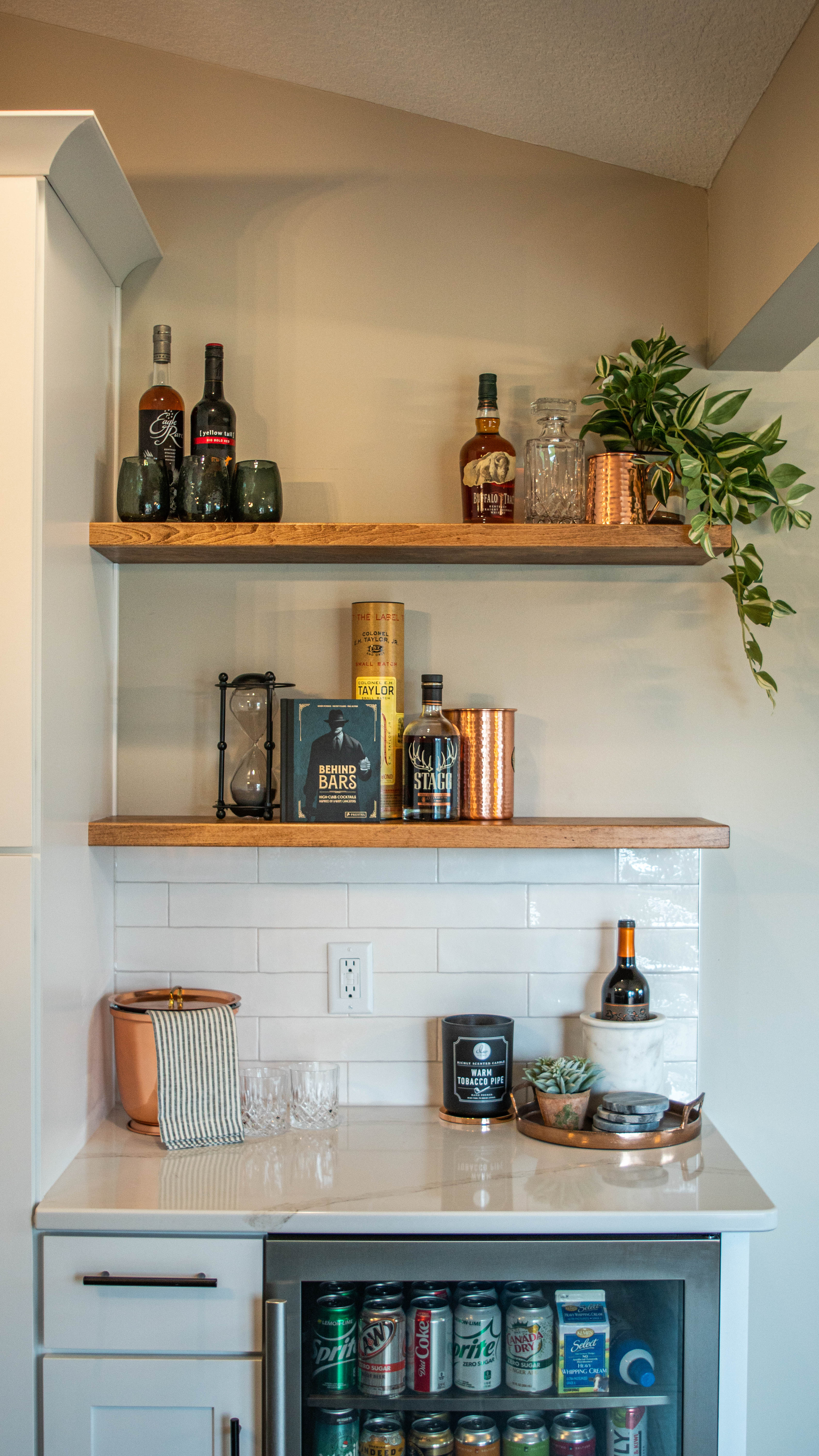 CliqStudios project: White shaker kitchen cabinets with white quartz countertops, wood floating shelves, and bronze accents