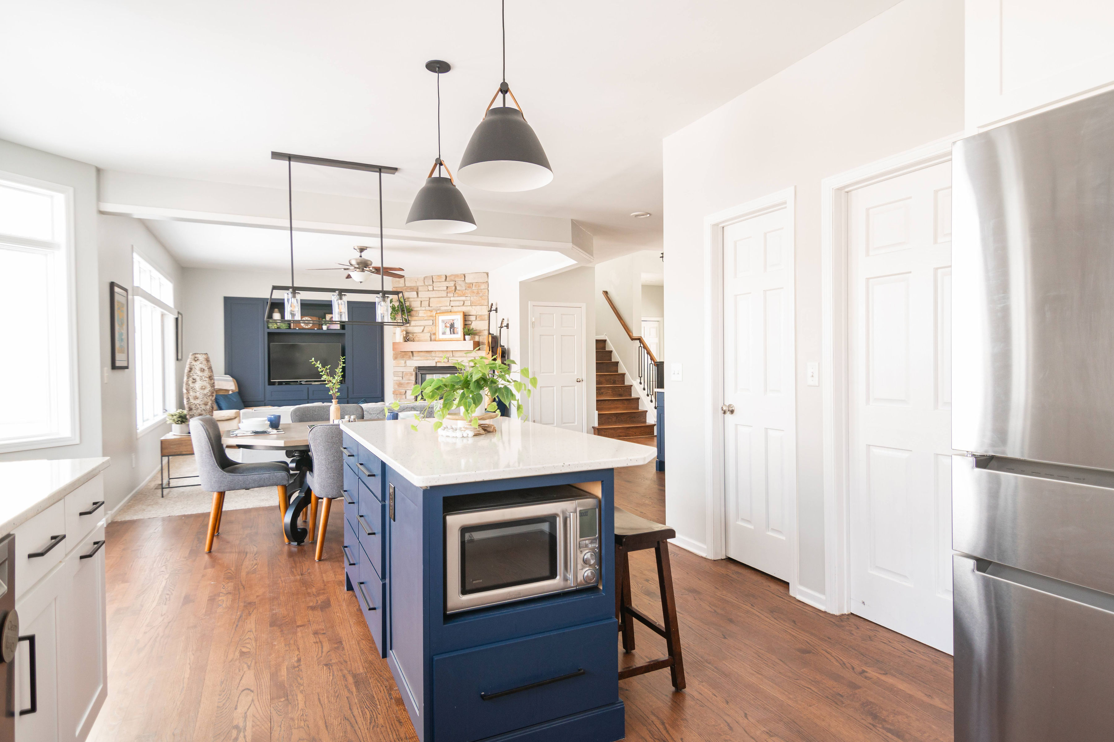 CliqStudios project: Blue shaker kitchen cabinet island with white countertop and modern black pendant lighting above