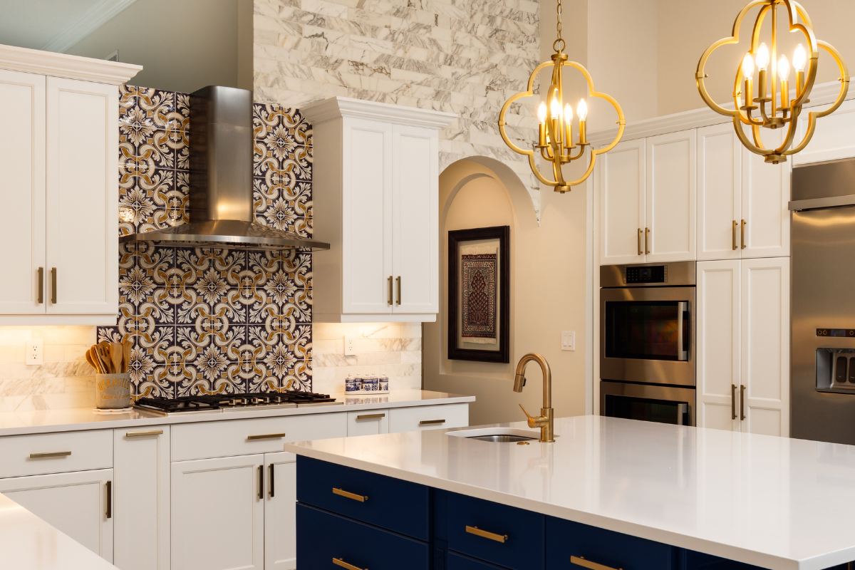 Open concept white and navy blue shaker kitchen design with a large island, gold hardware and pendant lights with designer backsplash tile