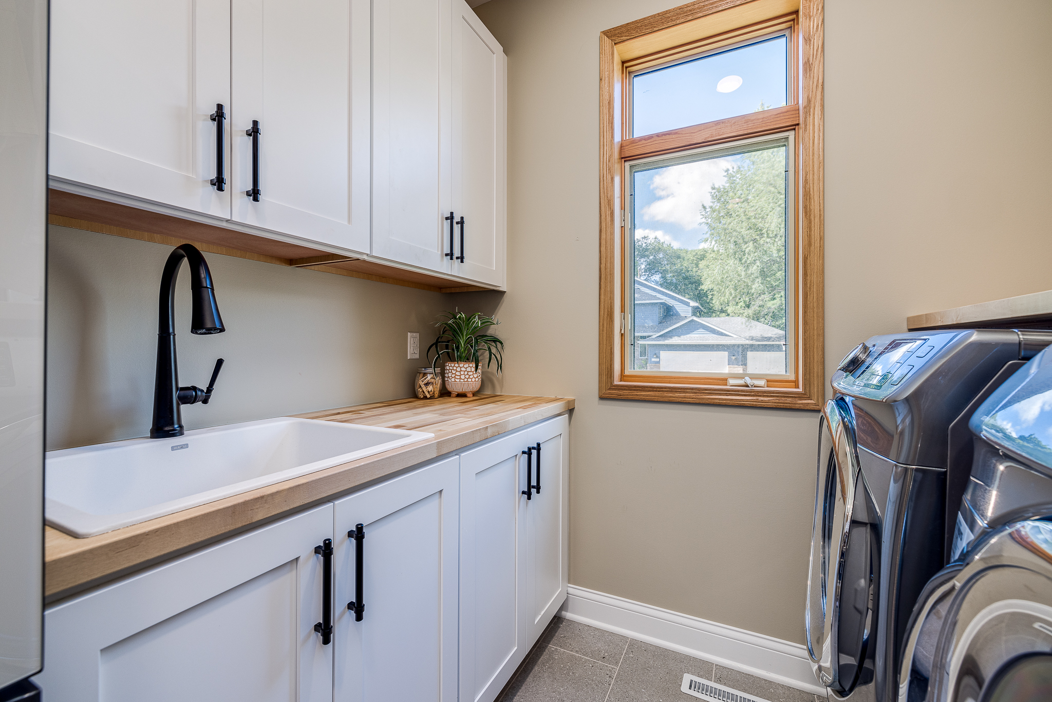 CliqStudios project: Shaker white laundry room sink cabinets with black hardware pulls and light butcher block countertops CliqStudios project: Shaker white laundry room sink cabinets with black hardware pulls and light butcher block countertops