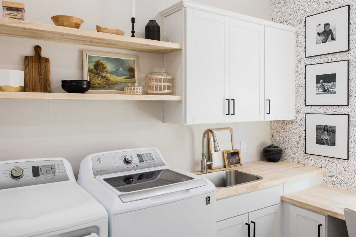 White shaker laundry room cabinets with a blonde wood butcherblock countertop