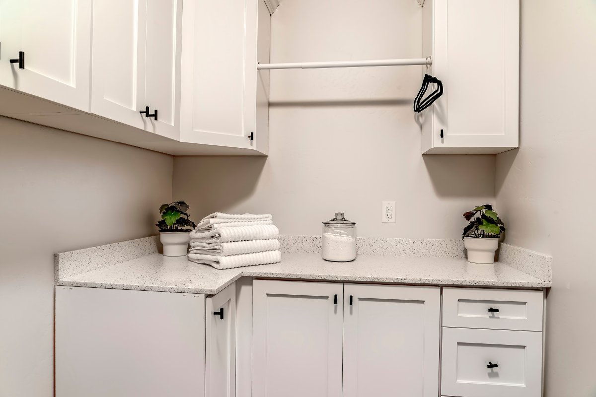 White shaker cabinet laundry room design with hanging rod above