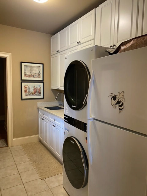 Stacked white laundry room cabinets with raised panel door style and tan countertops