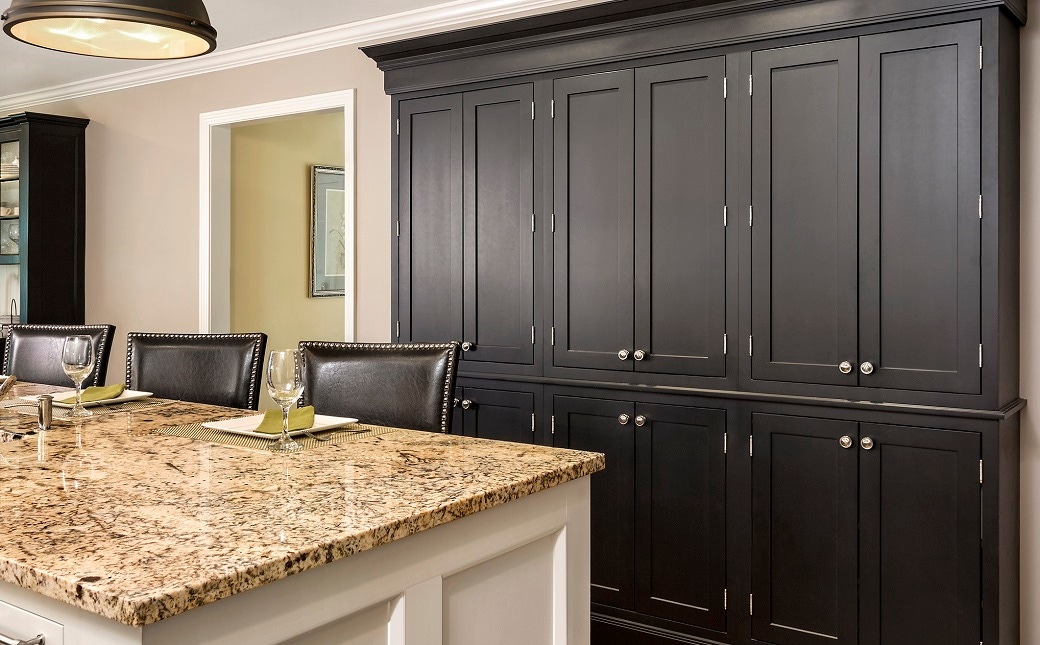 wall of black inset shaker cabinets with exposed nickel-plated hinge barrels and nickel knobs in kitchen with white island cabinets