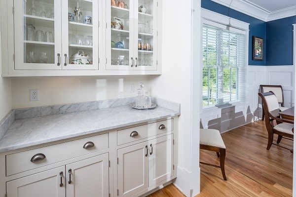 one wall of galley butlers pantry with painted white inset shaker cabinets and glass door storage on wall