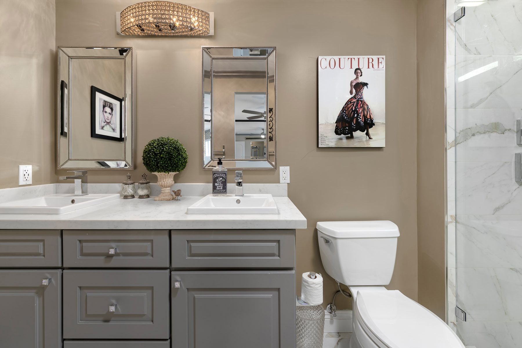 Medium-gray raised panel vanity cabinets with two drop-in sinks, white quartz countertops and taupe wall paint