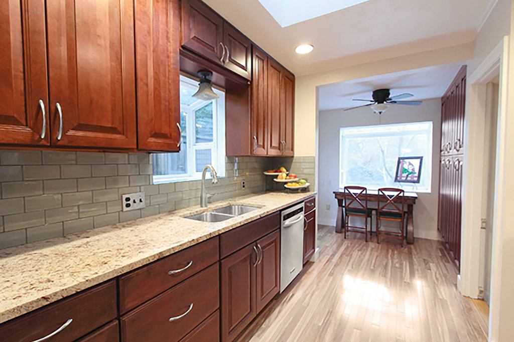 kitchen has raised-panel cherry cabinets, hardwood floors, bay window over the sink, skylight and picture window in the eating nook with pantry