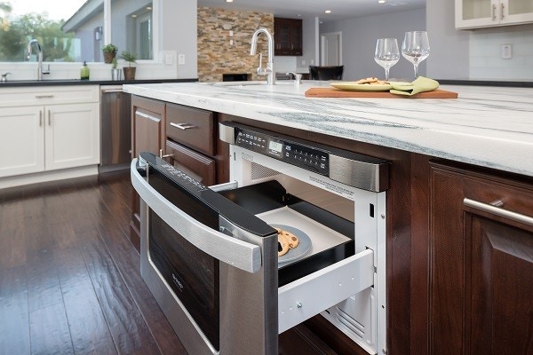 kitchen island built of cherry cabinets with microwave drawer and white marble countertop