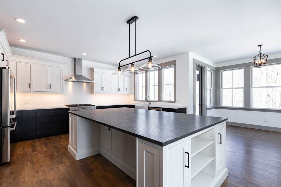 Large kitchen and island with white inset wall cabinets and dark brown base, and a white island with quartz countertops