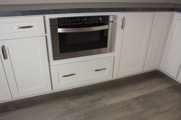 Microwave shelf with a gray countertop and gray flooring.