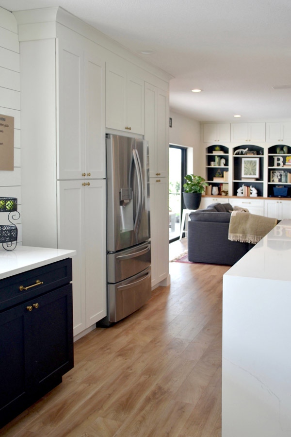 CLiqStudios Shaker cabinets in white, and in the center is a refrigerator. Next to it, base Shaker cabinets are in Black with white countertop.