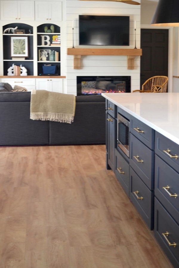 CliqStudios Shaker cabinets in Black used in an island with a white countertop. Behind that is a sitting area using CliqStudios Shaker cabinets in white for storage.