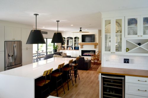 Full view of a kitchen using CliqStudios Shaker cabinets in Black and White. In the focus of the photo is a white butler's pantry and the island, with a white waterfall countertop.