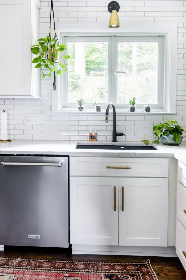 Kitchen corner with CliqStudios white Shaker cabinets, dark sink, and stainless-steel washing machine.