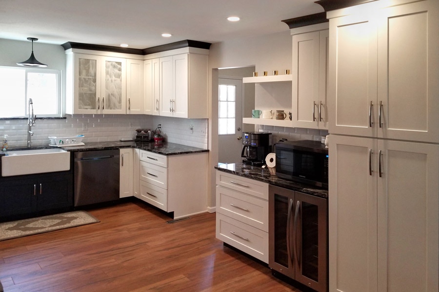 Black and white kitchen with wood floors, pantry storage and beverage center with mini fridge and floating shelves