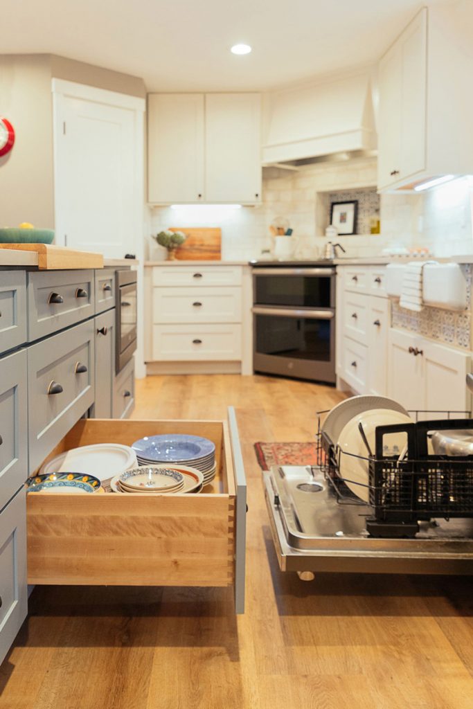 Open dishwasher and dish storage door open in white and blue kitchen