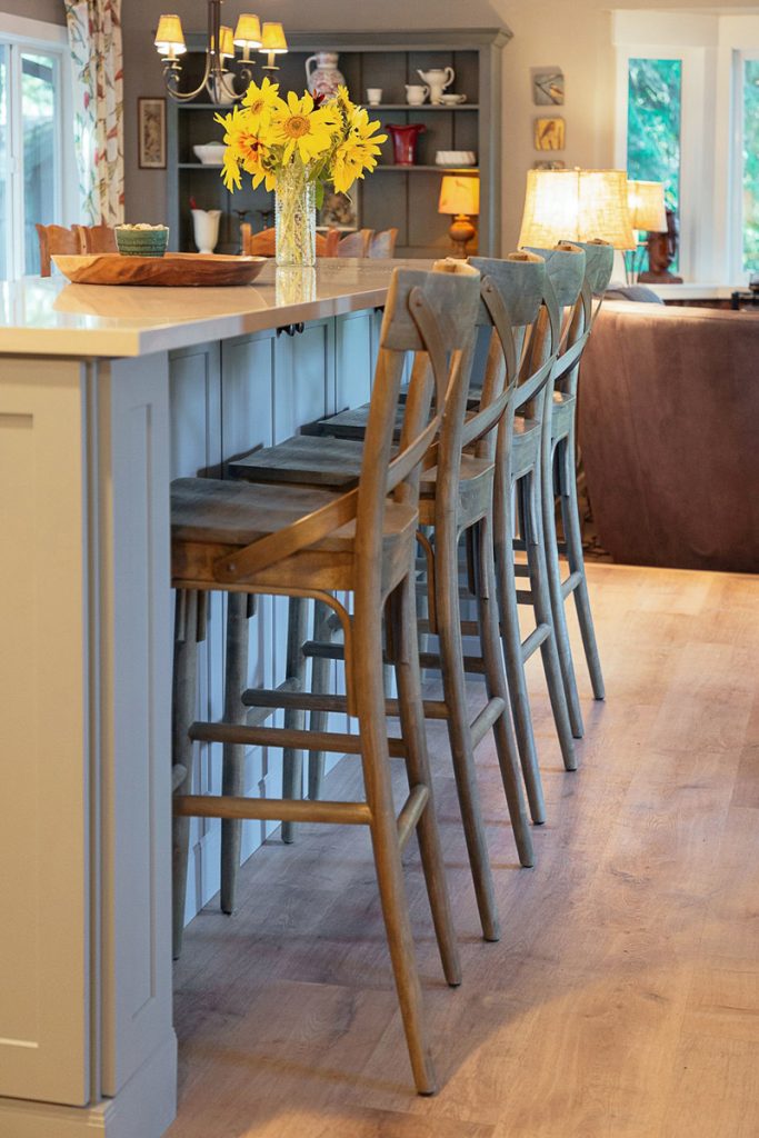 Four chairs at a blue kitchen island facing toward the living room