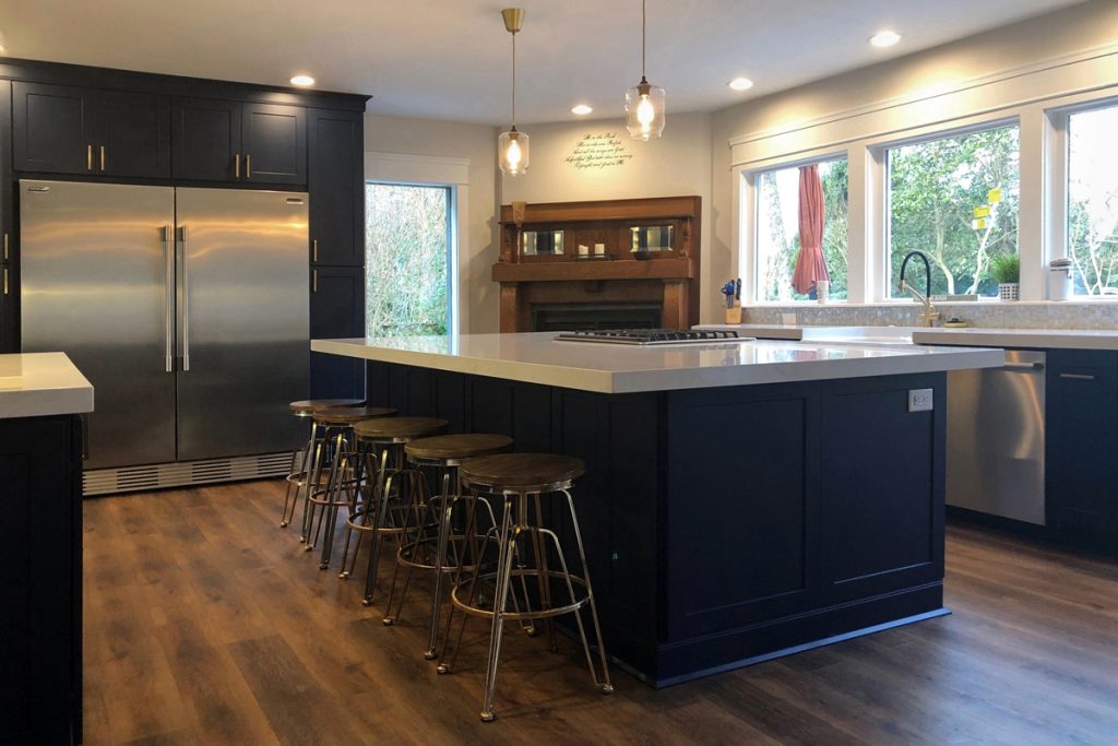 Blue and white kitchen with island seating facing large window above sink