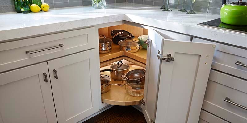 Kitchen base cabinet corner painted Light Gray with an upper and a lower lazy Susan on the interior.