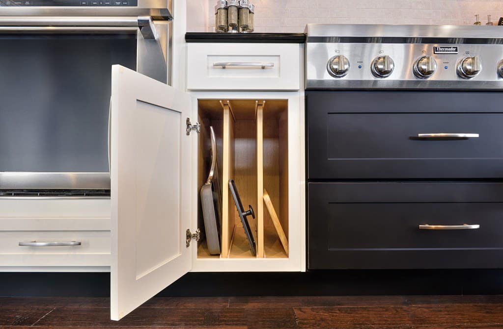 Smart storage solutions by CliqStudios keeps your kitchen organized with features such as this upright tray divider base cabinet, shown here in shaker cabinet style in painted White finish and paired with Shaker in painted Black finish