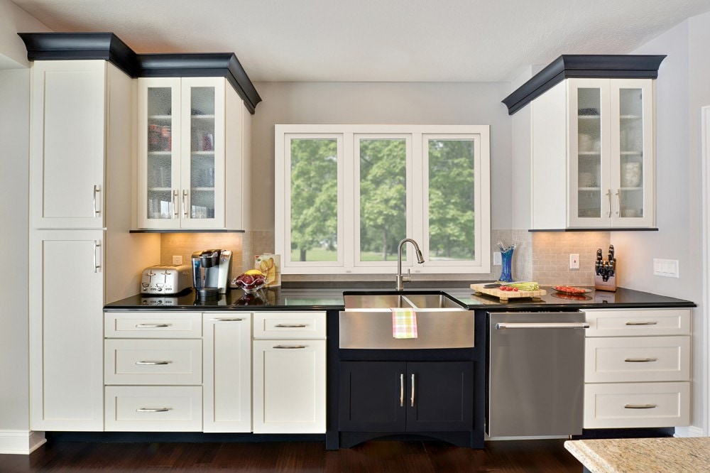 White cabinets with black crown molding and frosted glass doors frame kitchen window