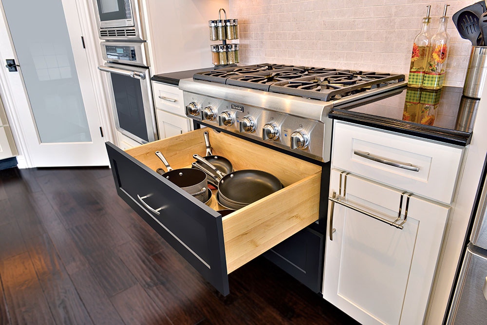 Deep storage drawer beneath pro gas cooktop in black and white kitchen