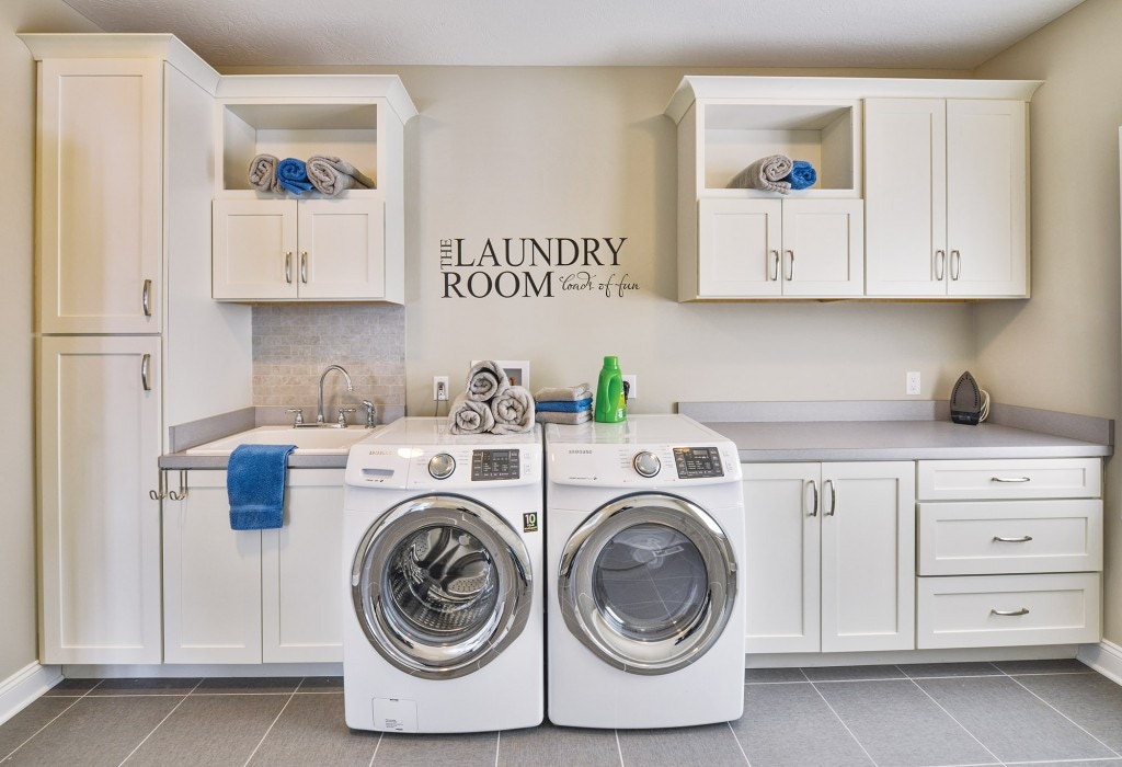 Spacious and bright laundry room custom built with CliqStudios.com shaker style cabinets. Shown Shaker cabinet style in painted White finish.