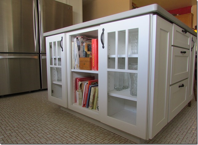 kitchen island built of white mission style cabinets with glass mullion doors and open shelves