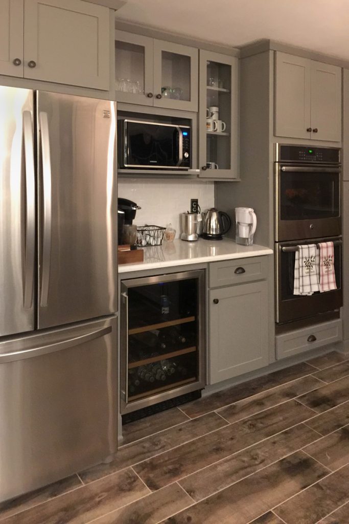 Kitchen beverage center with gray cabinets, wine fridge and glass front cabinets