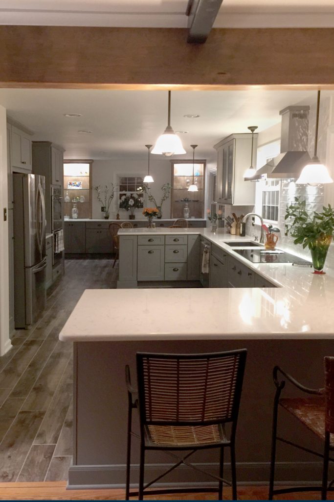 Kitchen with gray cabinets and exposed wood beams opens to the dining area