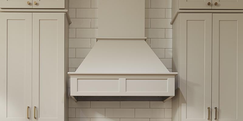 CliqStudios Shaker wall cabinets in Painted light gray with a chimneyed wood range hood in the shaker straight style