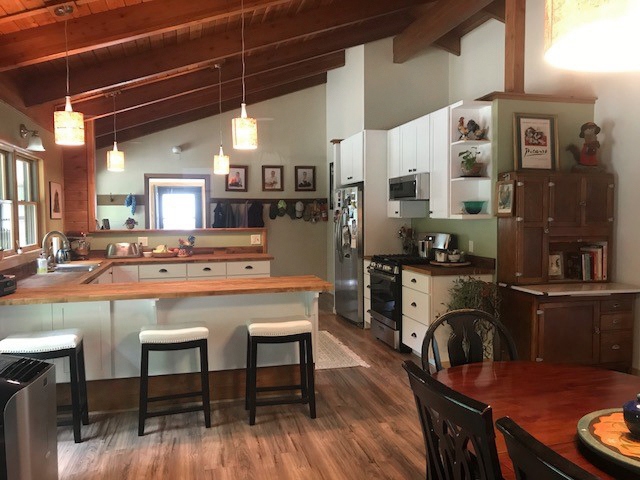 CliqStudios project: U-shaped white base kitchen cabinets with exposed wood beams above