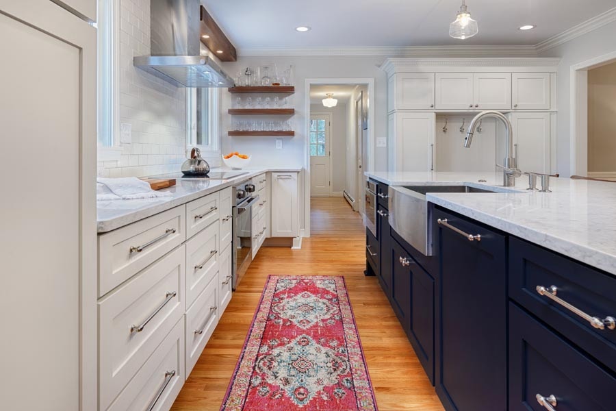 Modern two-toned shaker style kitchen in white and blue. Features open shelves, an oriental runner and stainless steel range hood.